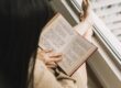 Mulher lendo livro com os pés na janela - melhores livros sobre yoga